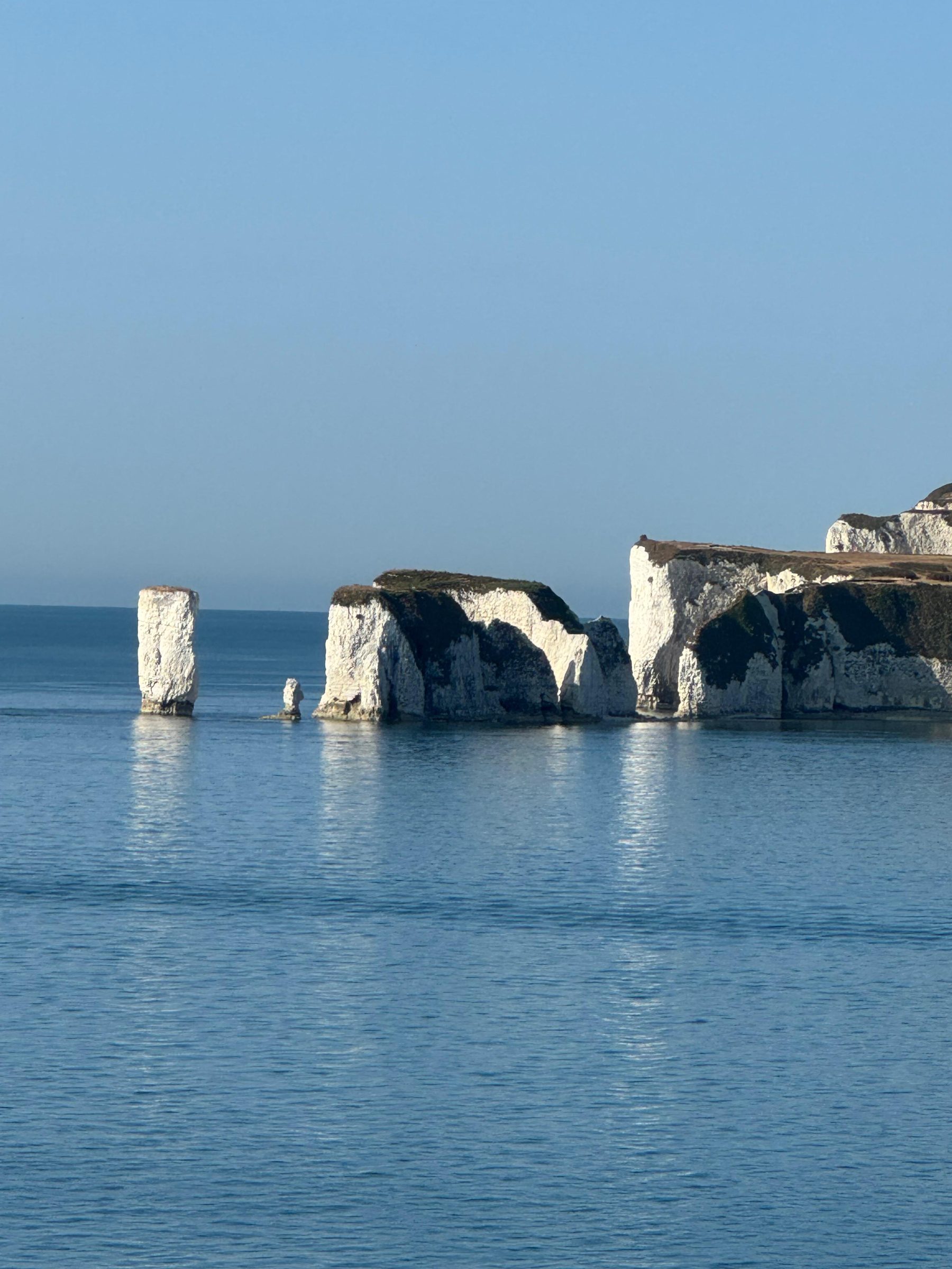 A single chalk sea stack standing apart from the cliff, worn by the water around it.