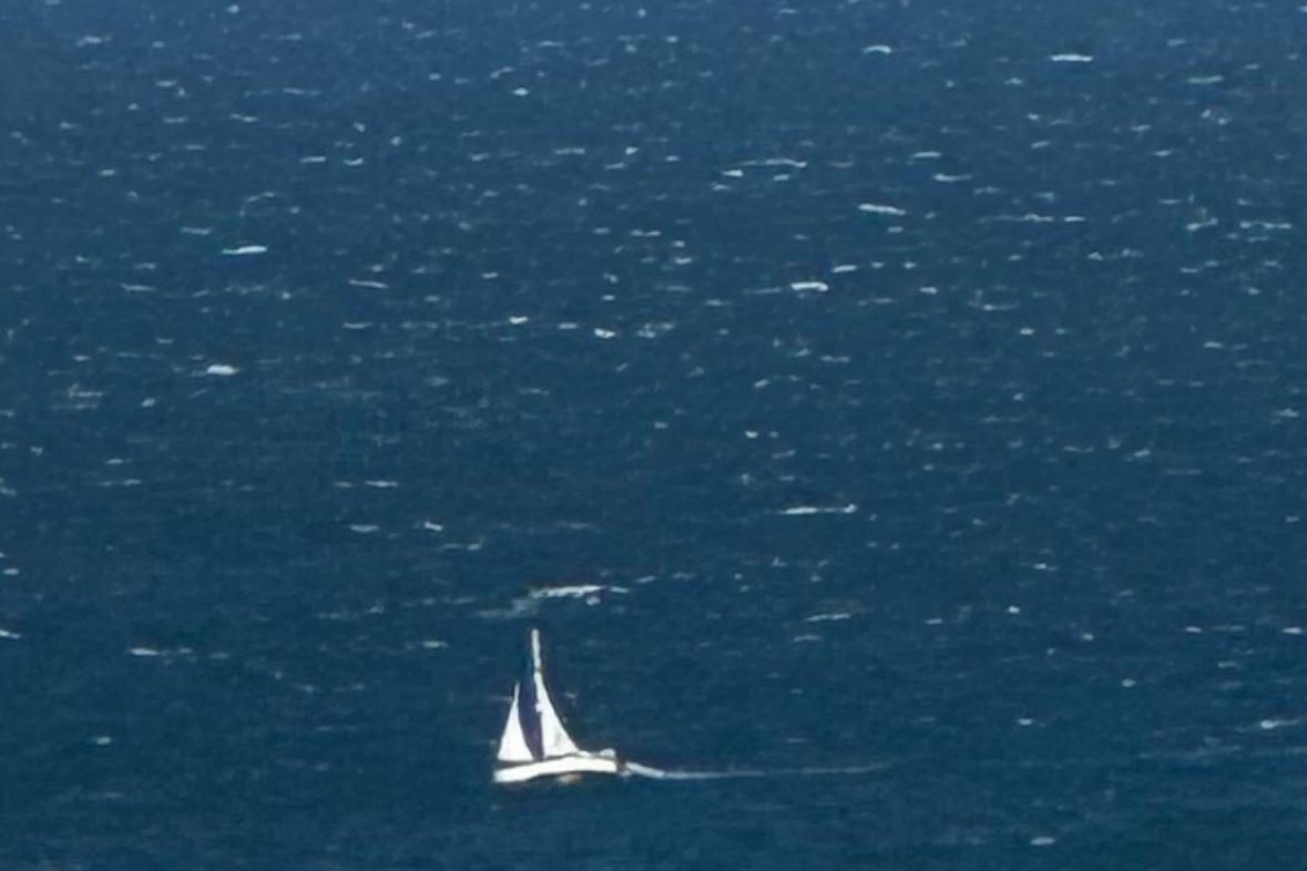 A small sailboat under way alone on open blue water.
